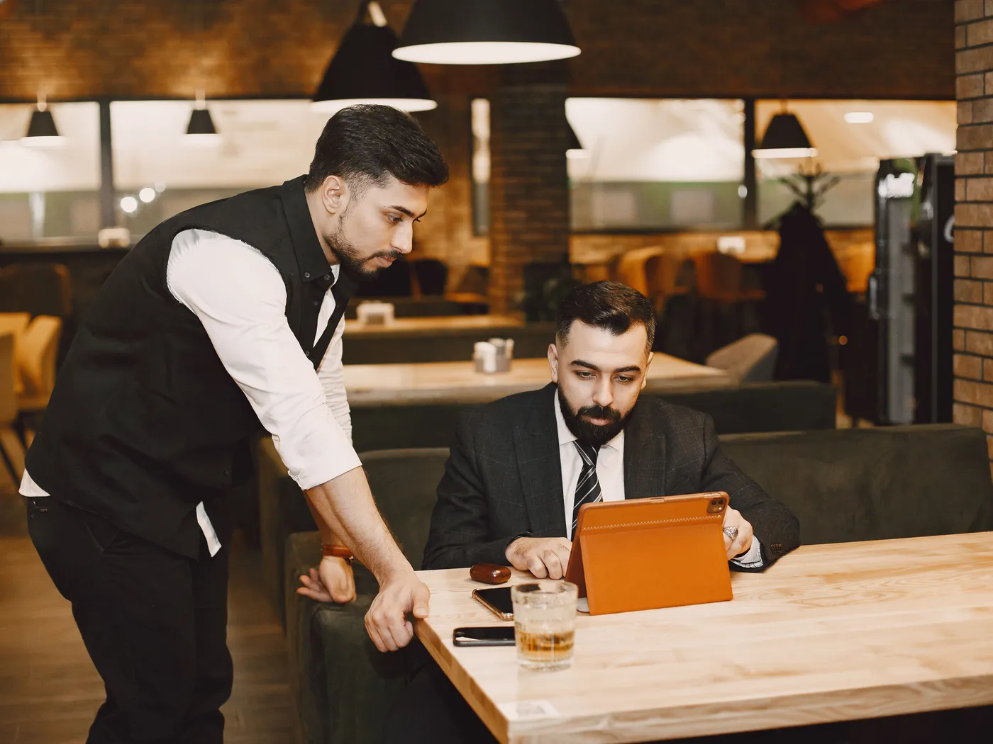 Restaurant manager and waiter reviewing a shift on a tablet